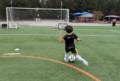 image (10) A young boy energetically kicks a soccer ball on a grassy field, showcasing his enthusiasm for the game.