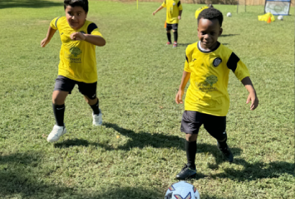 A group of young boys energetically playing soccer on an indoor field, showcasing teamwork and enthusiasm.